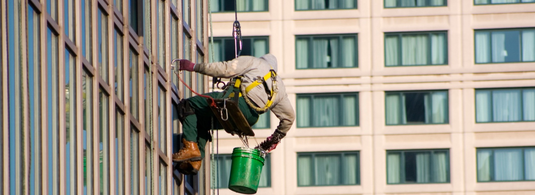An expert window washer hanging on the side of a building in Illinois