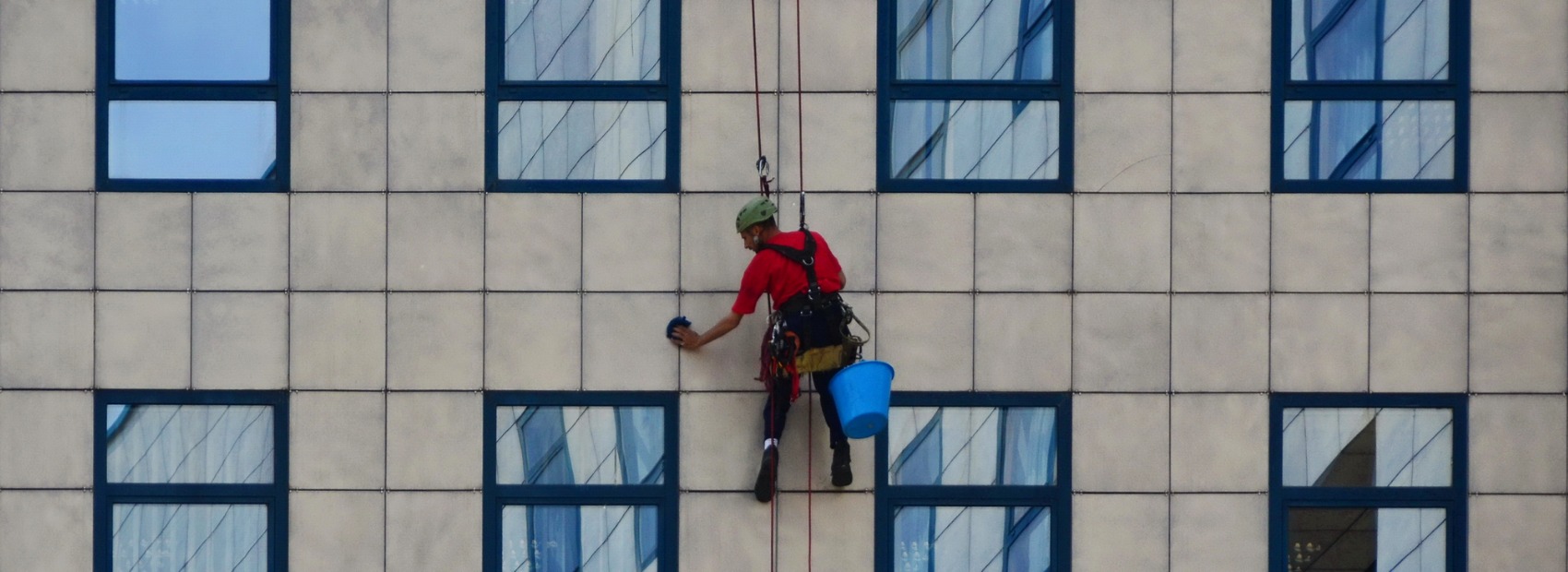A window cleaner slides down to provide high-rise window cleaning services