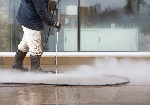 A team member from All Window Cleaning Services tackles pressure washing on a sidewalk
