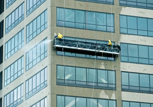 Workers from All Window Cleaning Services work on pressure washing windows for a Chicago office.